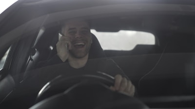 Man laughing while talking on phone in car