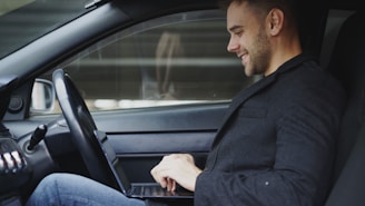 Man working on laptop inside a car
