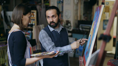 Artist teaching student painting in studio