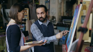 Artist teaching student painting in studio