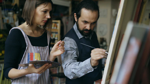 Two artists painting on canvas in studio.