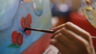 Hand painting red flowers on a blue canvas.