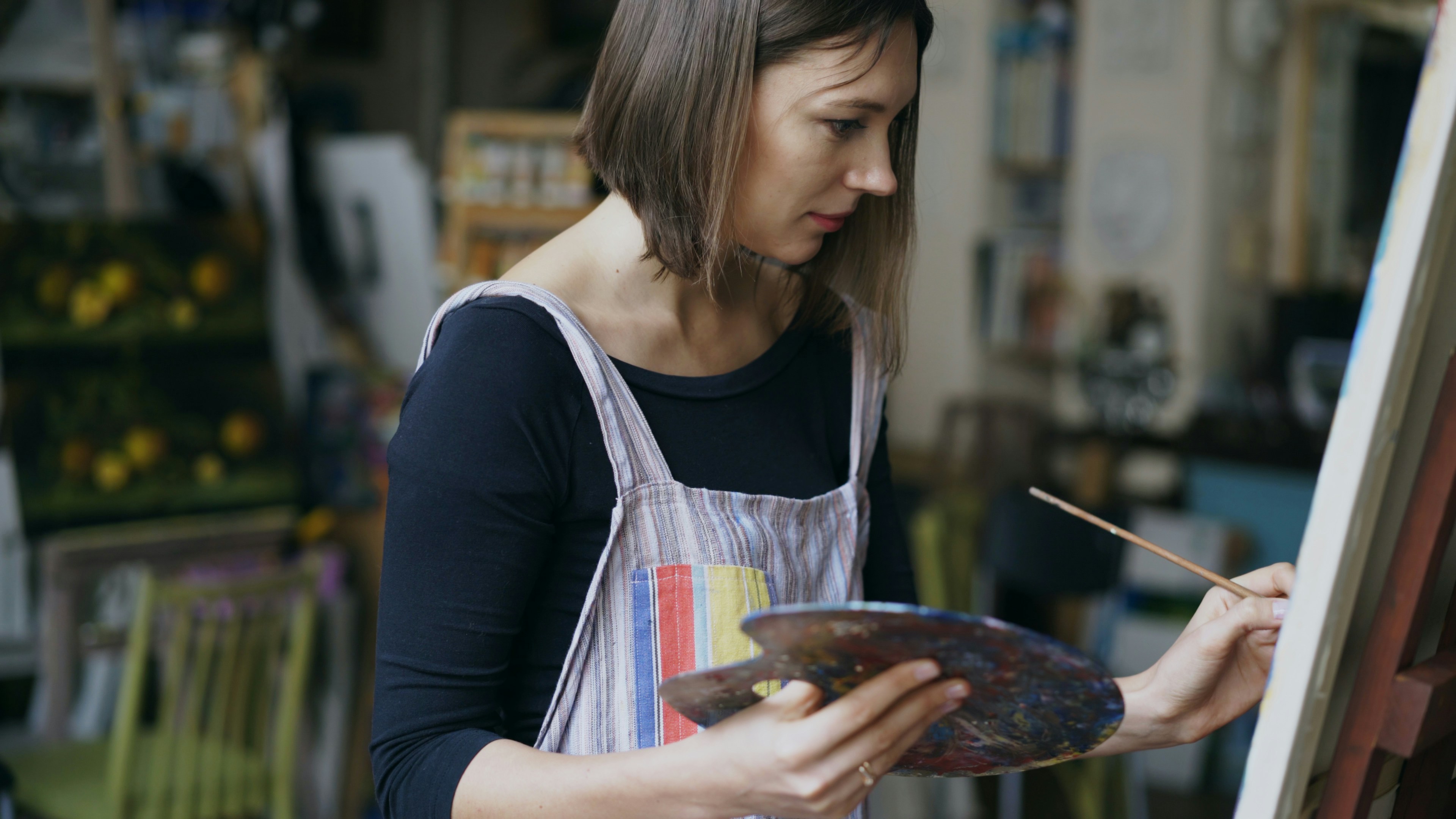 팔레트를 사용하여 스튜디오에서 캔버스에 그림을 그리는 아티스트.