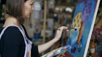 Artist painting a colorful abstract artwork on canvas.