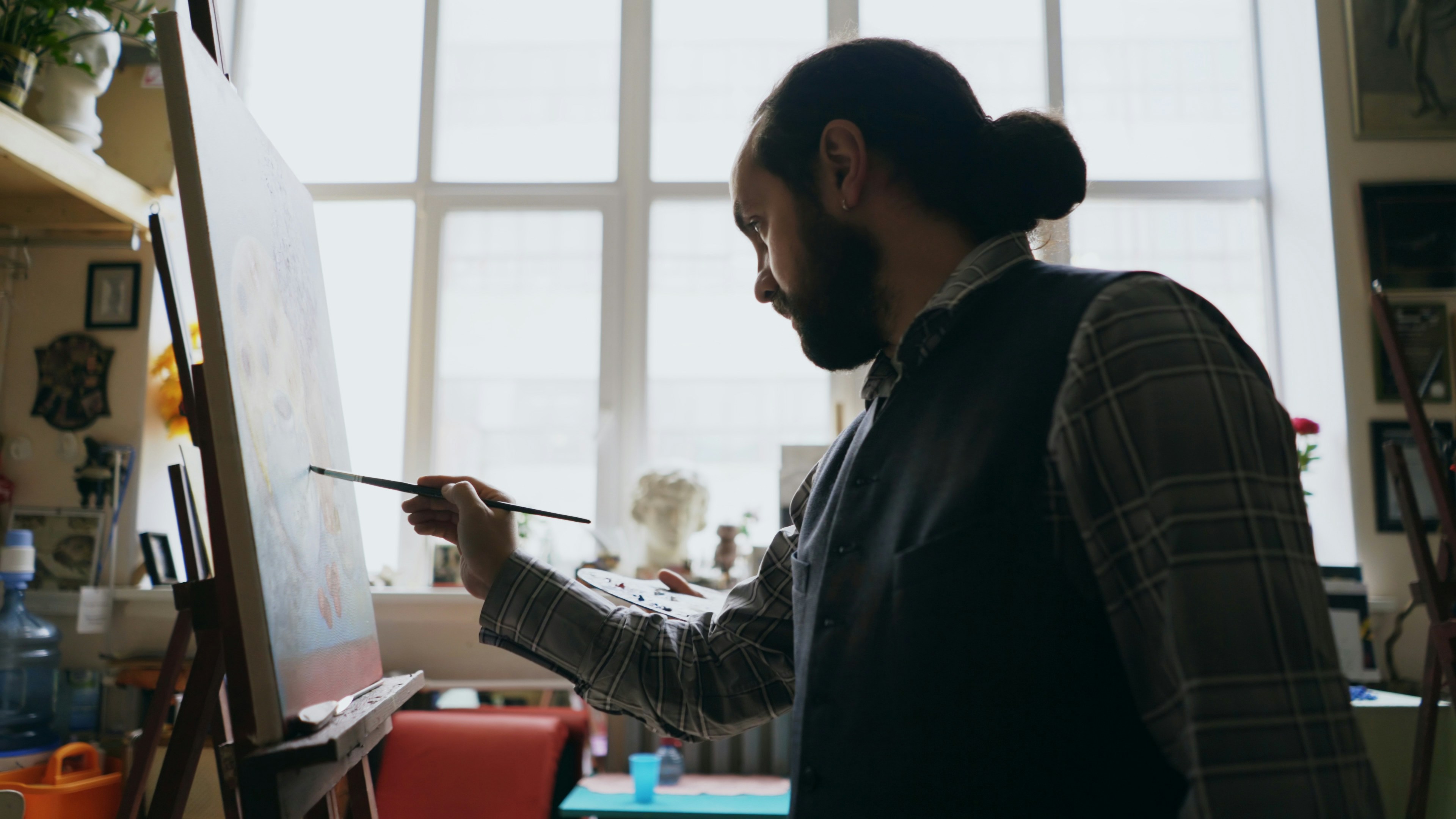Skilled artist man teaching young girl painting on easel at art school studio