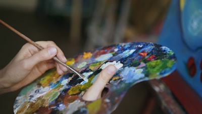 Artist mixing paint on a colorful palette with brush.