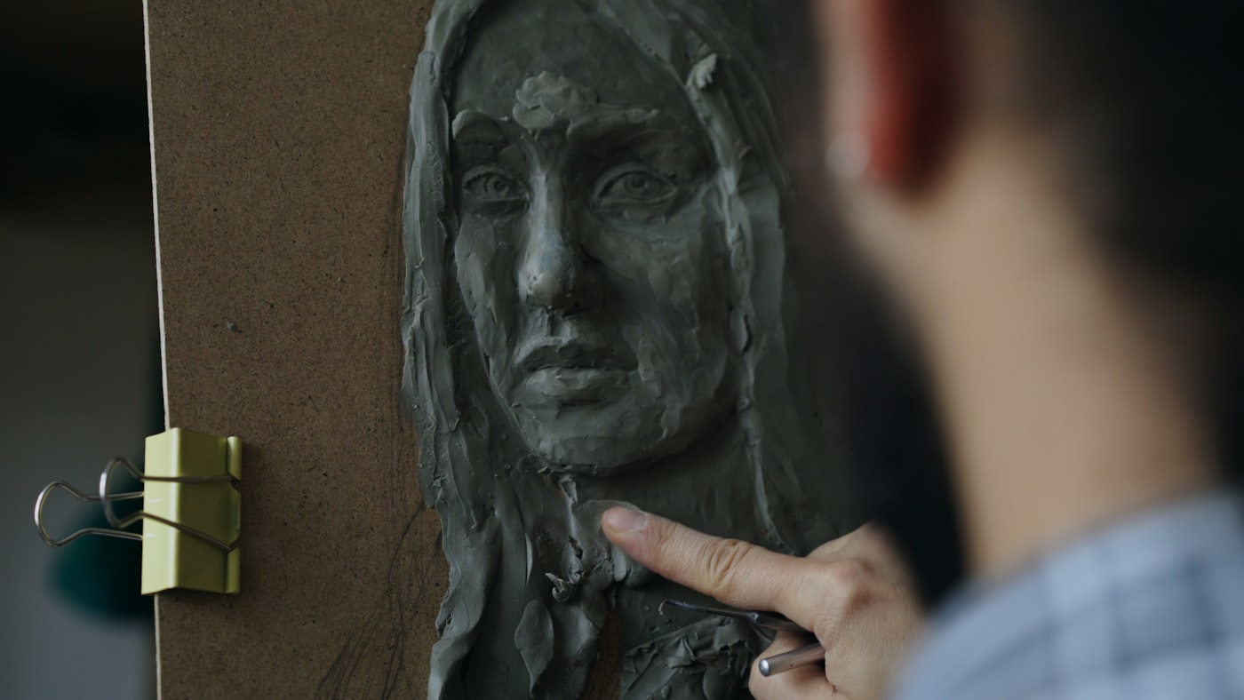 Künstlerin modelliert eine Figur in einer Werkstatt