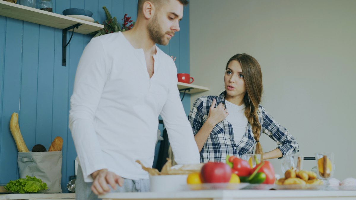 Couple in a tense kitchen conversation, a common scene for why do I get defensive when criticized