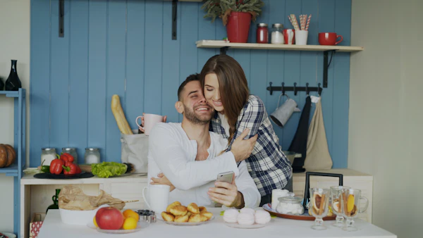 Couple s’embrassant et souriant dans une cuisine