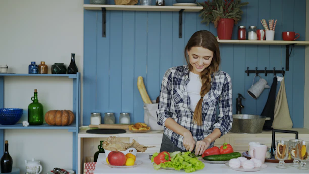 A woman is chopping vegetables in a kitchen.