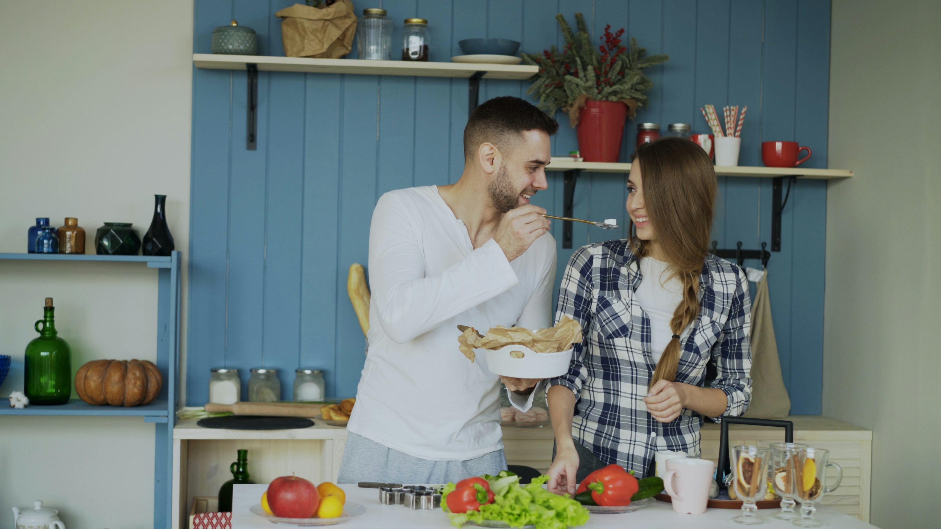 Couple cooking together in a blue kitchen.