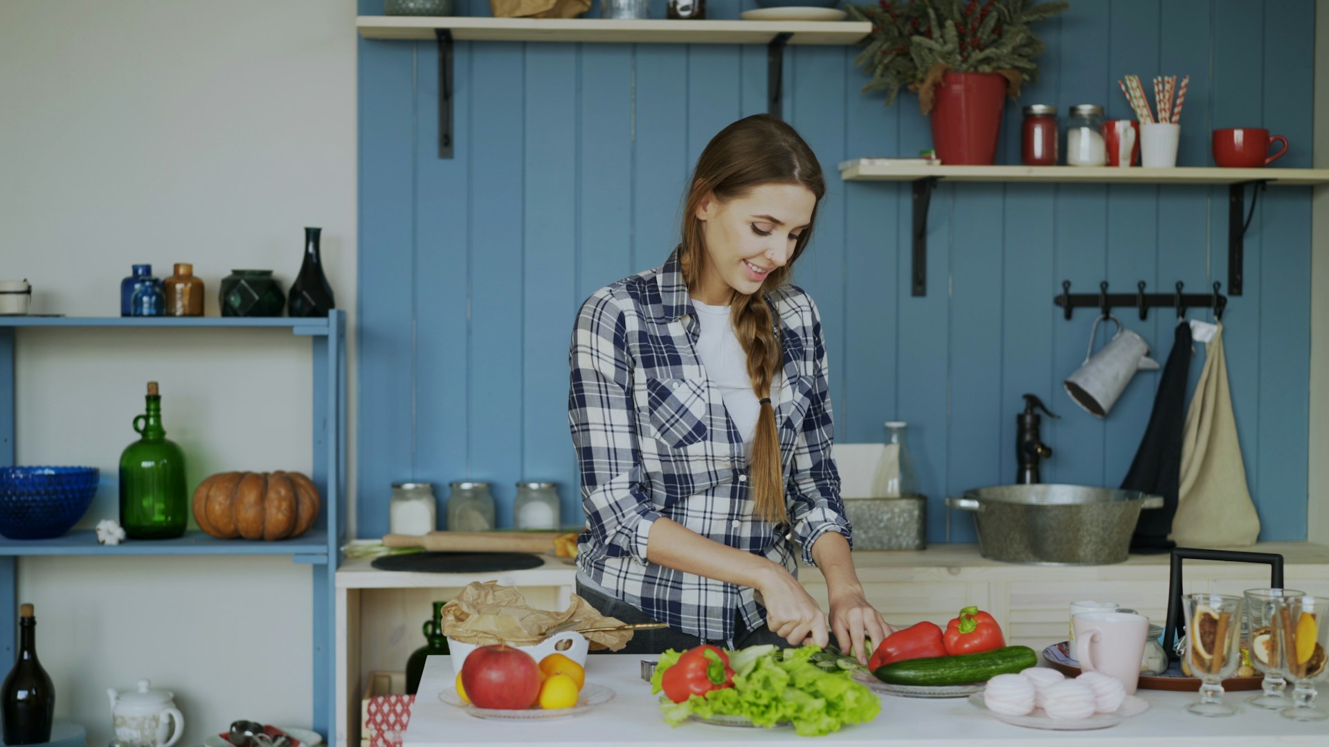 Woman chopping vegetables in a blue kitchen