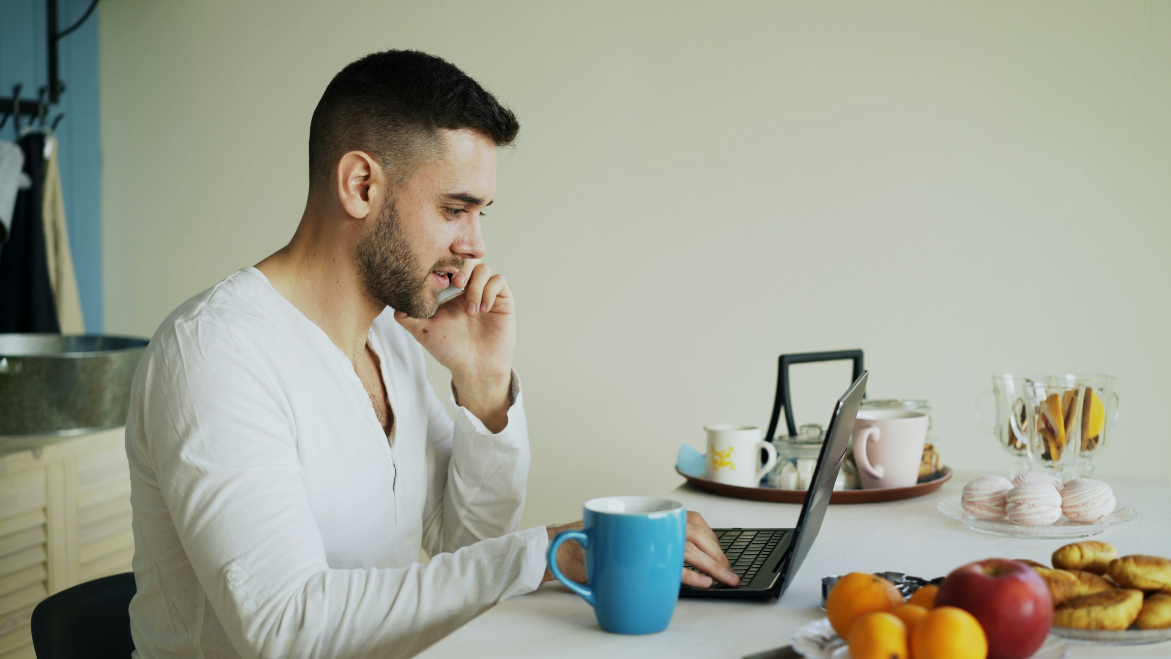 Young man using laptop and talking on phone
