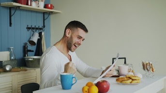Man laughing while looking at tablet in-ear headphones