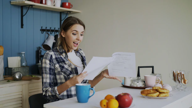 Woman with surprised expression reading documents at table.