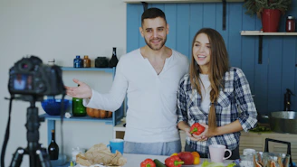 Couple filming a cooking tutorial in a kitchen.
