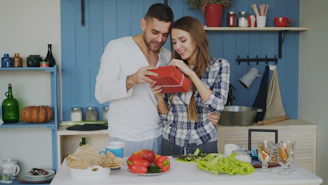 Couple opening a gift in a kitchen