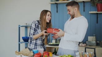 Woman gives man a gift in the kitchen