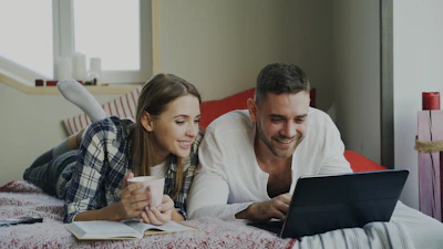 Couple looking at a laptop on a bed