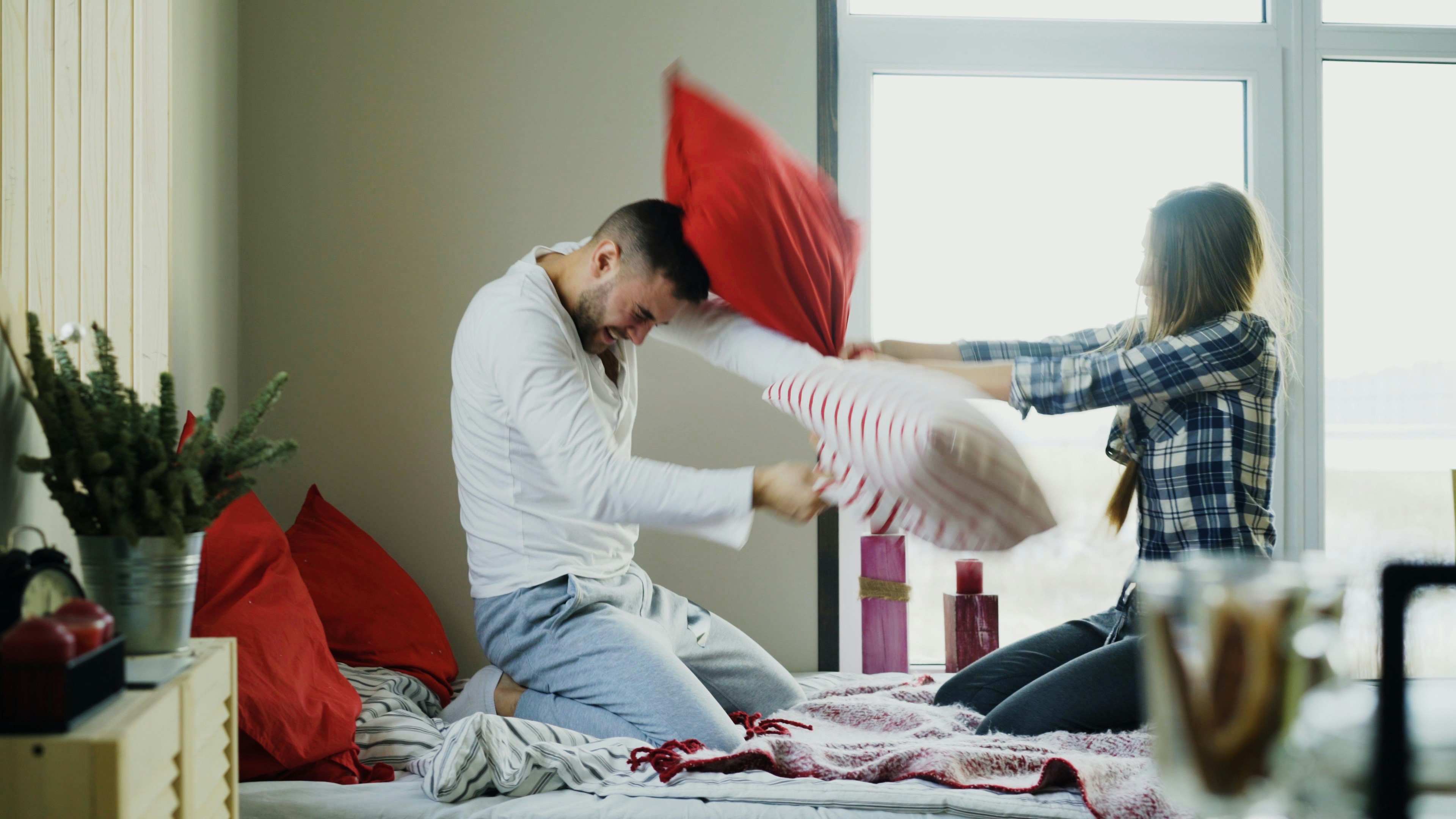 Couple having a playful pillow fight on bed