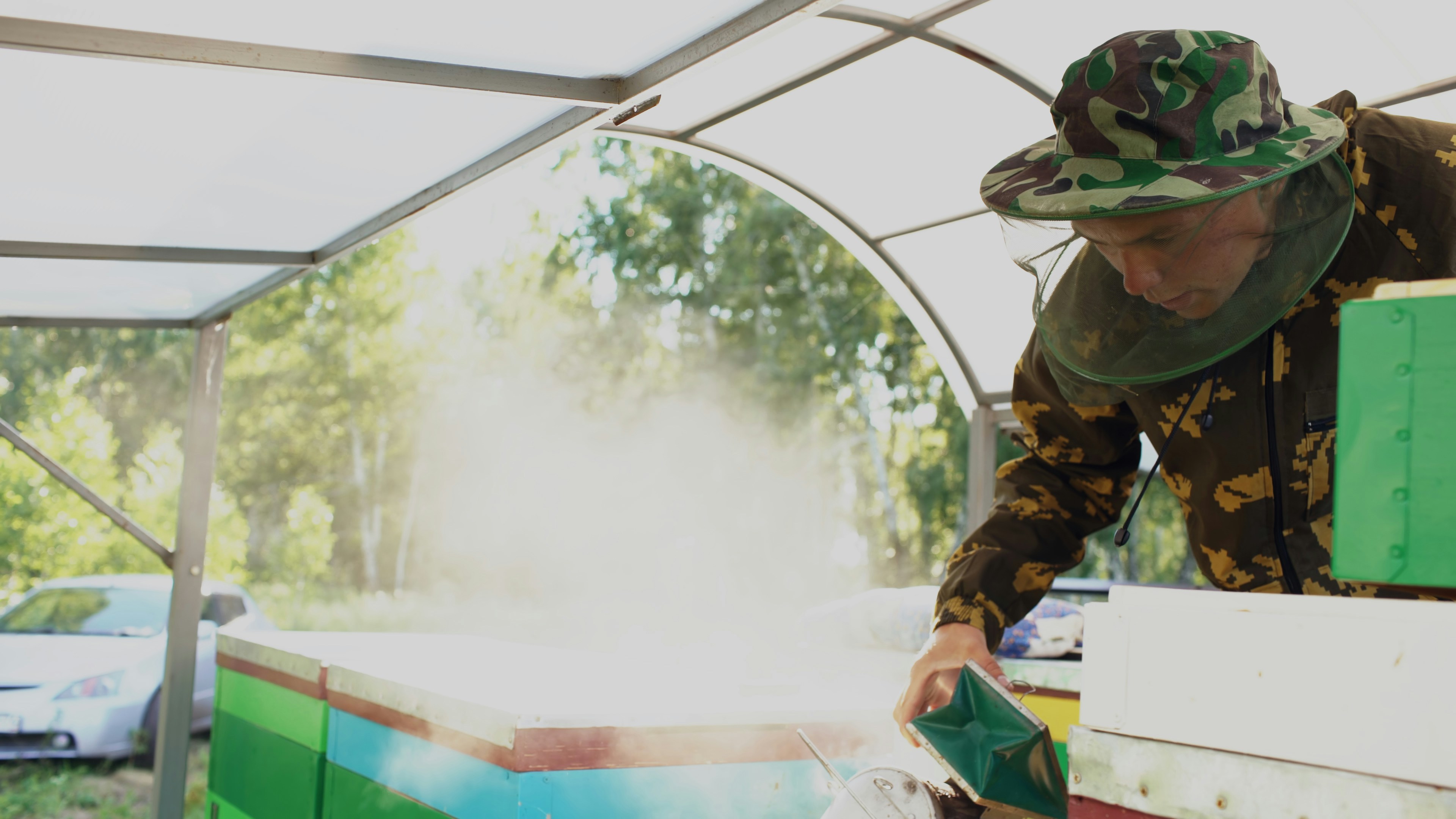 Beekeeper spraying a beehive with white powder.