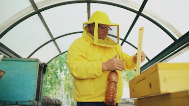 Beekeeper in yellow suit working with beehives