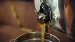 Golden honey streams into a metal container.