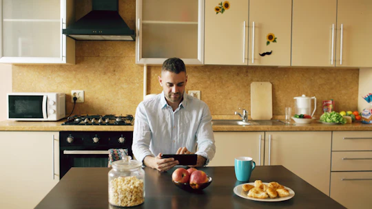 Man using tablet in modern kitchen with breakfast items.