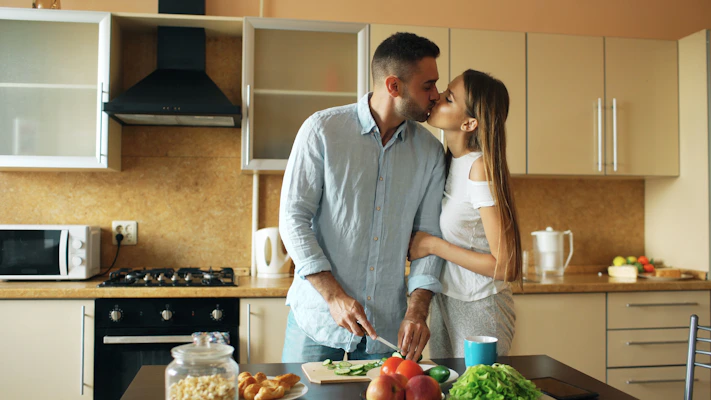 Couple kissing while preparing food in kitchen