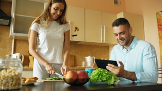 Couple preparing food and using tablet in kitchen.