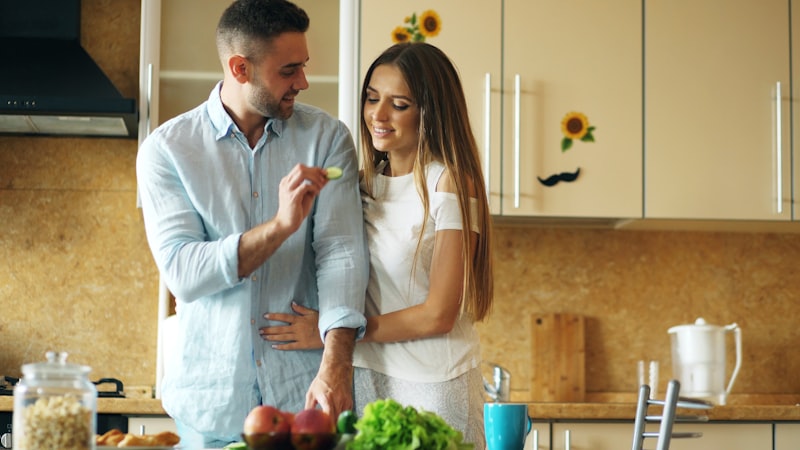 Couple happily cooking together in a bright kitchen.