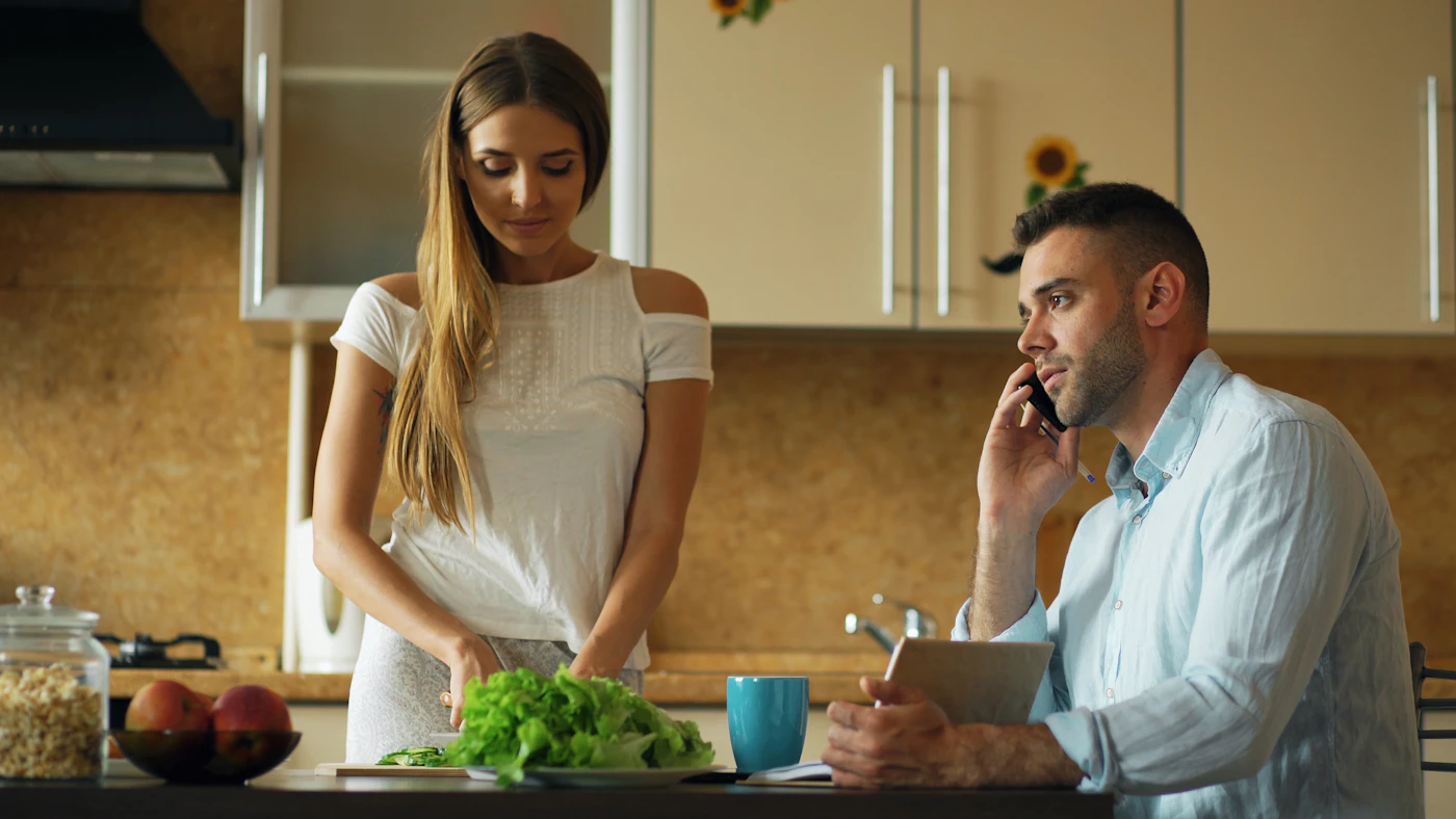 Couple dans la cuisine, femme hachant de la laitue, homme au