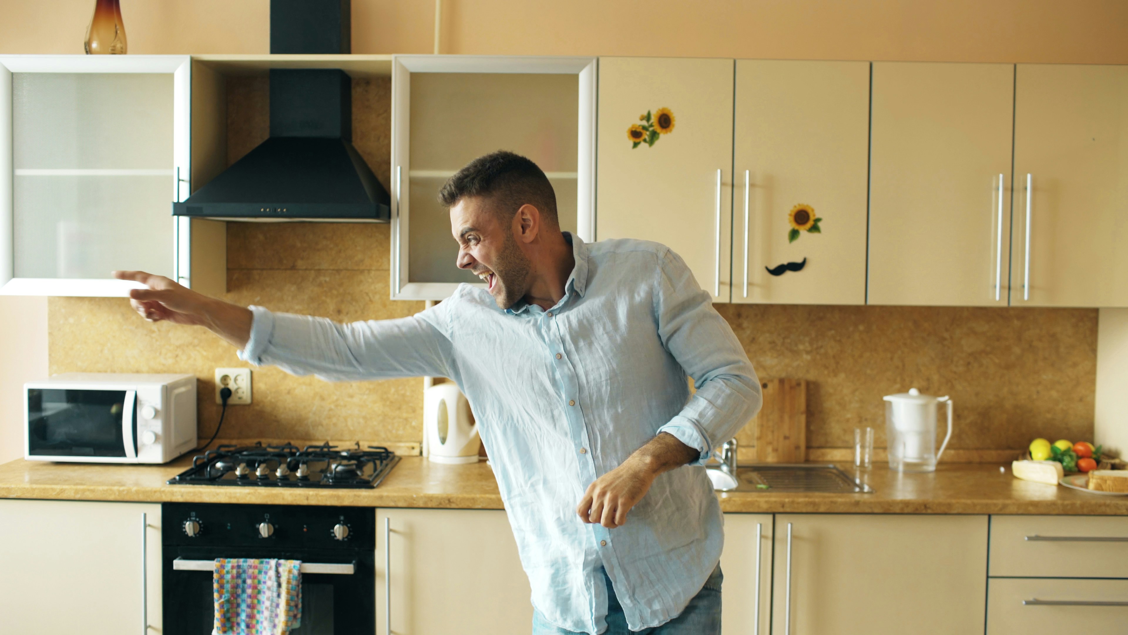 Handsome young funny man dancing in kitchen at home in the morning and have fun on vacation