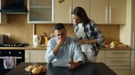 Couple looking stressed over bills at kitchen table.