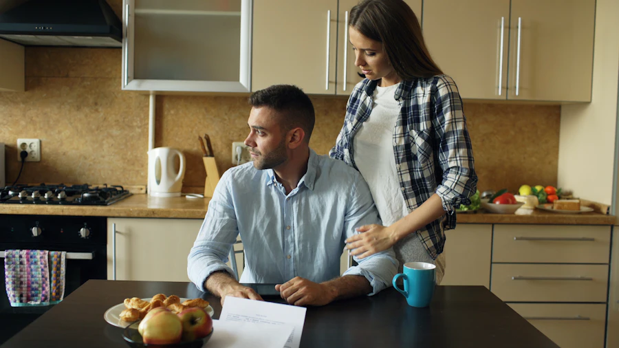 A young couple in their kitchen reviewing a document together over coffee