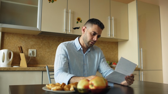 Man reading document at kitchen table with fruit and fruit