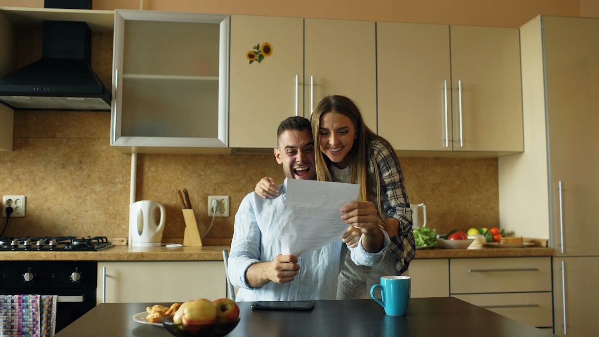 Couple in kitchen reviewing crisis volunteer sign-up sheet with smiles and enthusiasm