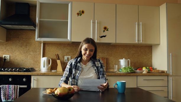 Woman reading document at kitchen table with coffee