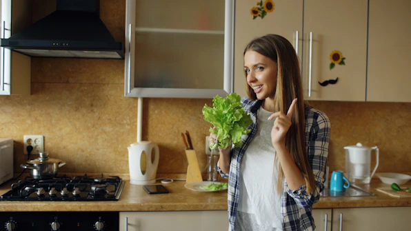 Young woman holding lettuce in a kitchen