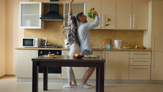 Couple dancing and singing in a modern kitchen