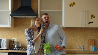 Couple singing in kitchen with tomato and lettuce
