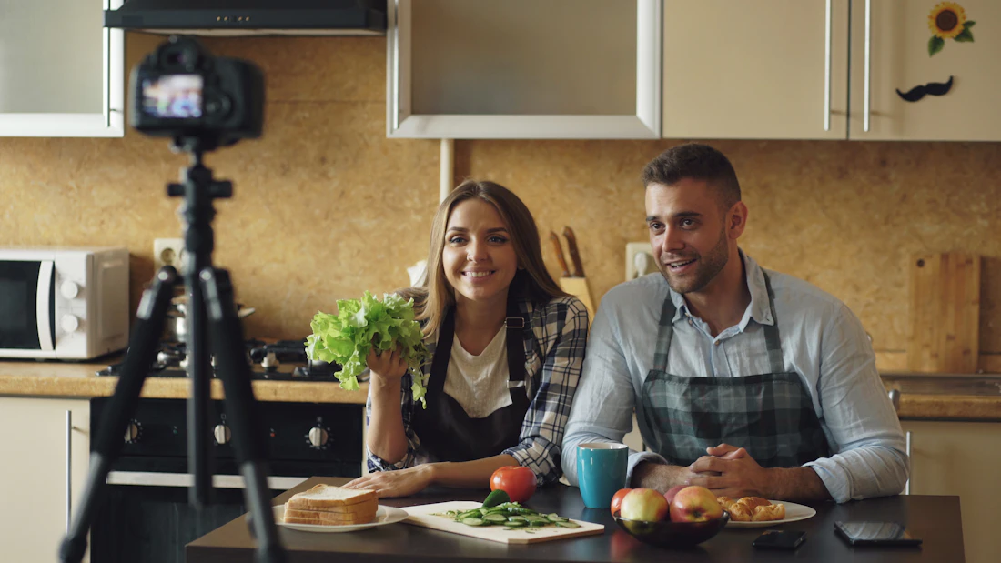 Two small business owners filming a cooking video in their kitchen