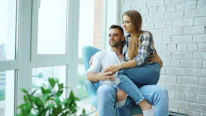 Couple sitting in a chair by the window.