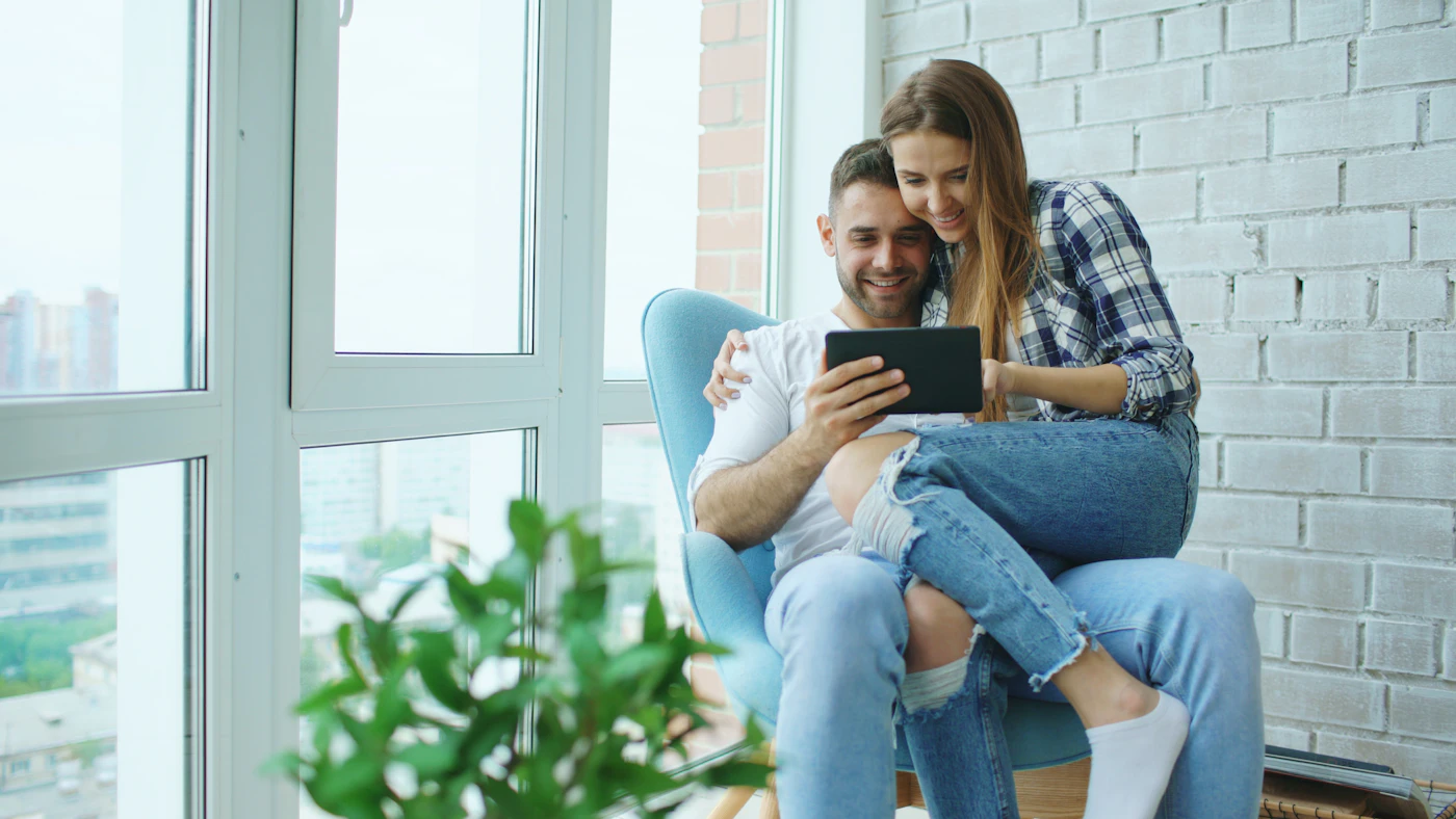 Couple sitting together and discussing something on a tablet, representing partnership and shared planning