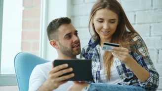 Couple using tablet and credit card for online shopping.