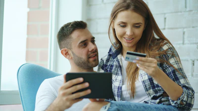 Couple using tablet and credit card for online shopping.