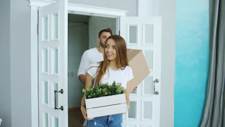 Couple carrying boxes into a new home