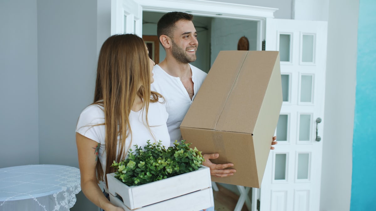 Zwei Personen tragen gemeinsam Umzugskartons beim Entrümpeln einer Wohnung