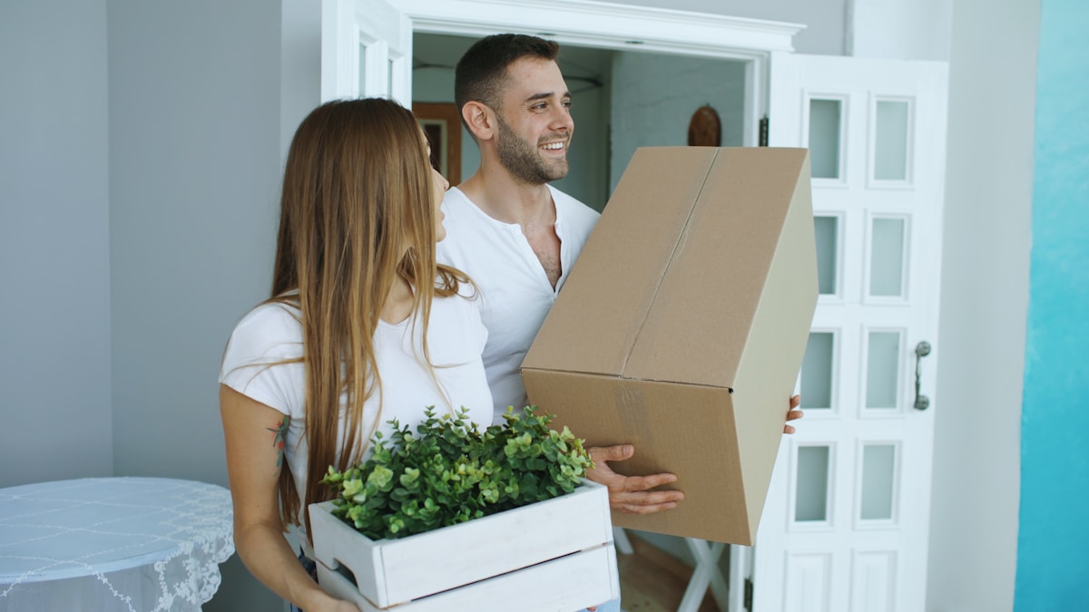 Young couple carrying moving boxes into their new apartment on move-in day