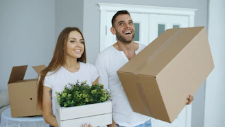 Couple holding moving boxes and plant
